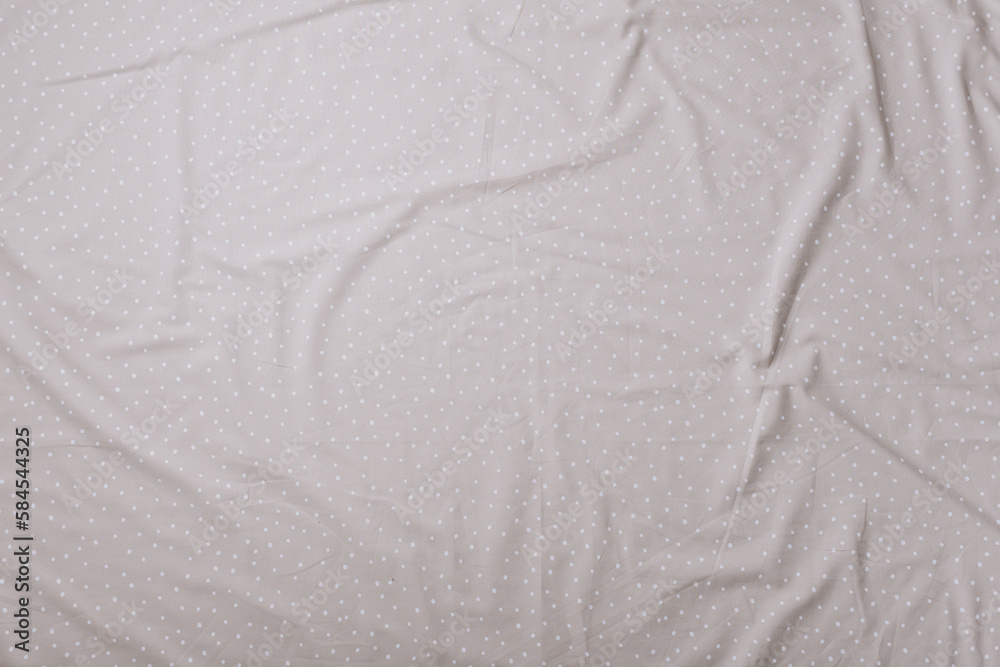 Naklejka premium Top view of wrinkles on beige spotted bed sheet. Bed linen texture. Copy space