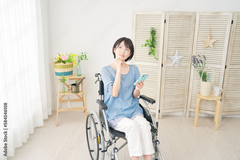 リビングでスマホを使いながら想像する車椅子に乗った女性 リビングでスマホを使いながら想像する車椅子に乗った女性