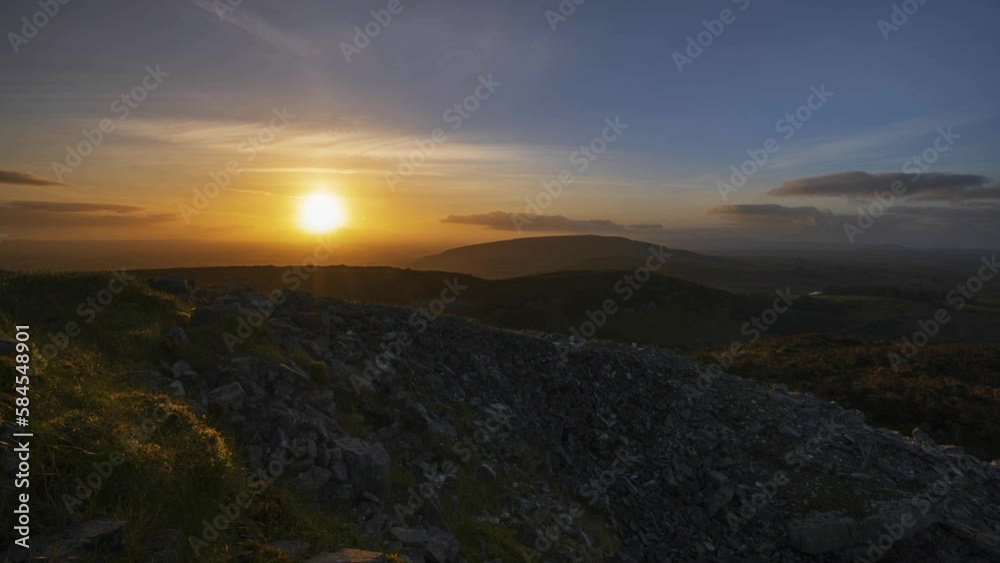 Timelapse of rural nature landscape with ruins of prehistoric passage tomb in the foreground during dramatic sunset viewed from Carrowkeel in county Sligo in Ireland. Timelapse of rural nature landscape with ruins of prehistoric passage tomb in the foreground during dramatic sunset viewed from Carrowkeel in county Sligo in Ireland.