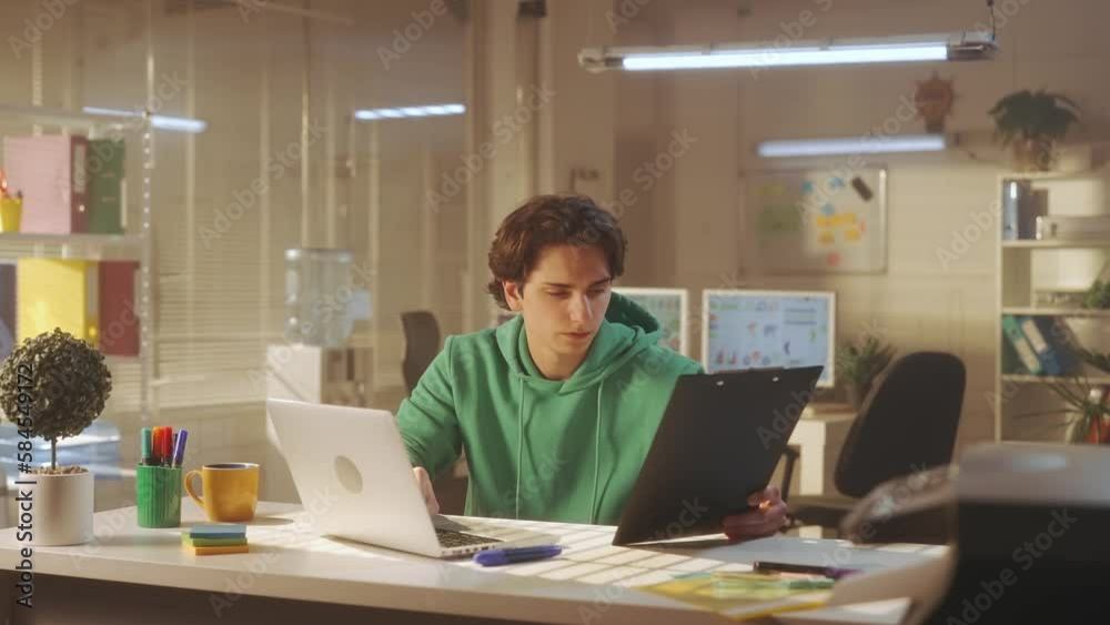 A young man is typing on a computer keyboard, looking at his watch and finishing his working day. A tired manager in a green sweatshirt closes his laptop and wearily rubs his eyes. A young man is typing on a computer keyboard, looking at his watch and finishing his working day. A tired manager in a green sweatshirt closes his laptop and wearily rubs his eyes.