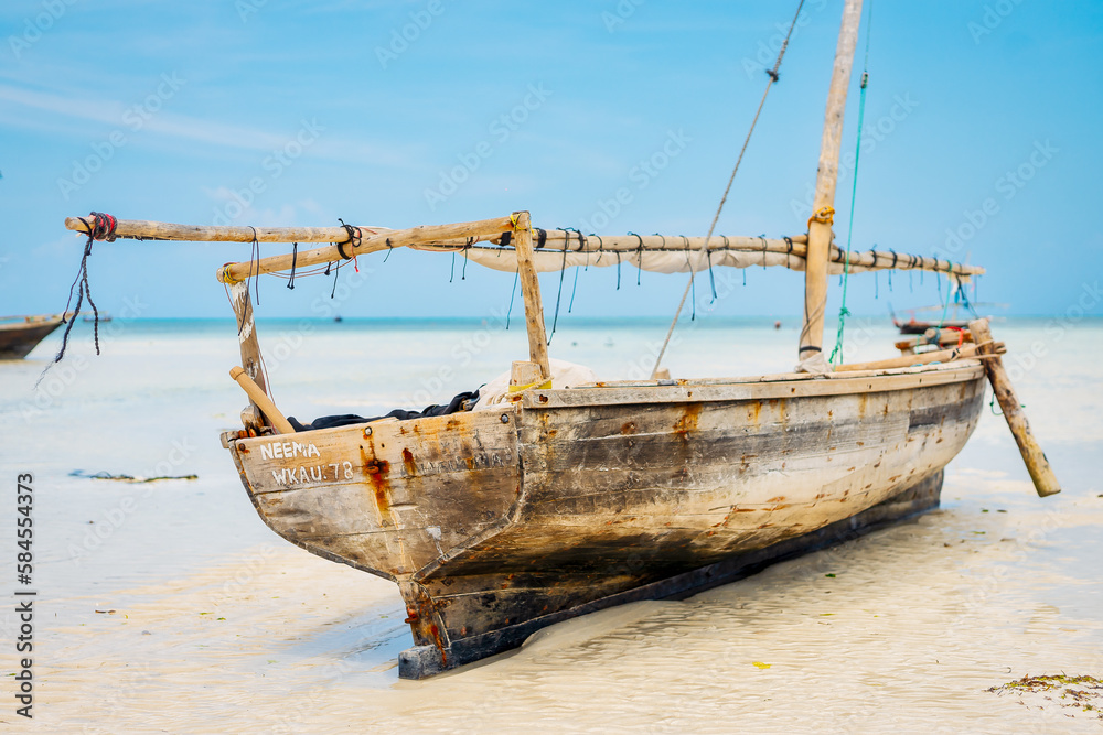 Near a tropical island, a traditional Zanzibar fishing boat lies in clear water close to the beach, perfect for summer travel and fishing boats