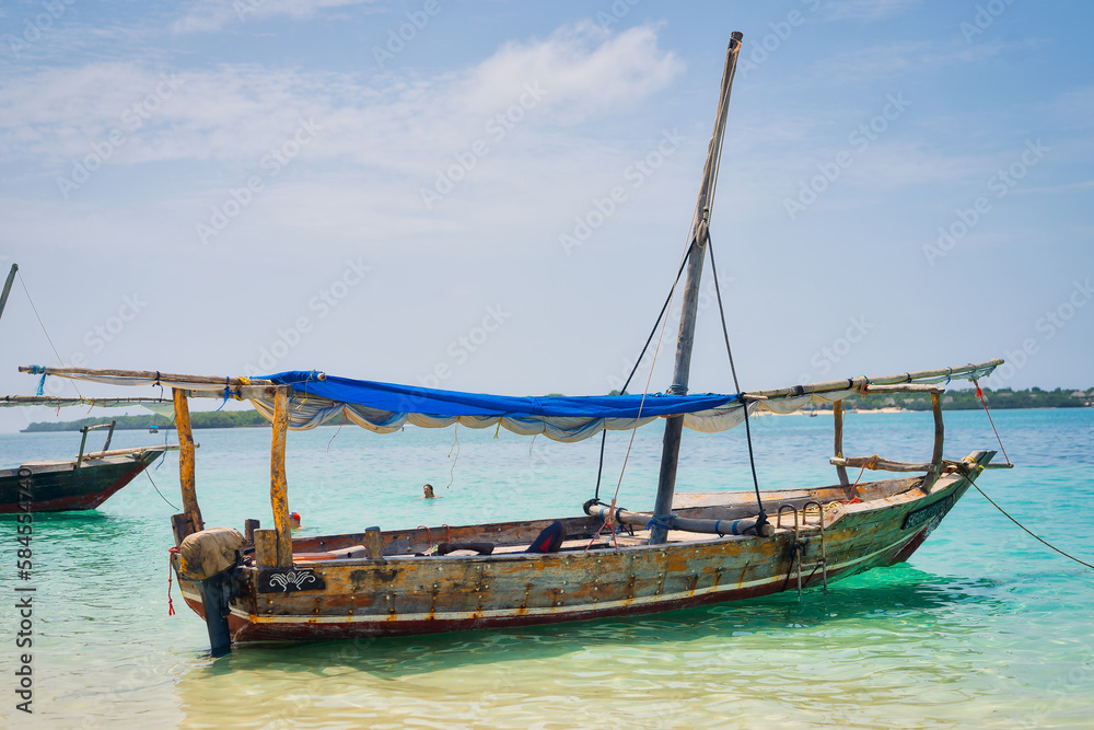 Experience the beauty of Zanzibar's tropical coast from a bird's eye view, with fishing boats resting on the sandy beach at sunrise. The top-down perspective showcases clear blue waters, green palm 