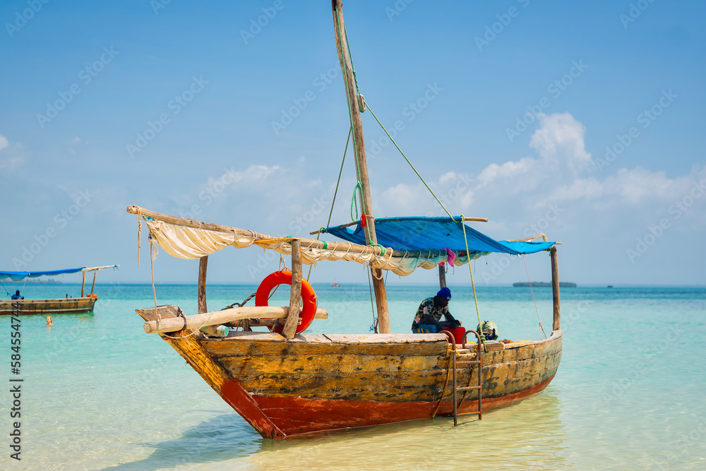 Experience the beauty of Zanzibar's tropical coast from a bird's eye view, with fishing boats resting on the sandy beach at sunrise. The top-down perspective showcases clear blue waters, green palm 