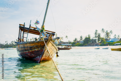 Experience the beauty of a traditional Zanzibar fishing boat as it rests in the clear waters near the beach of a tropical island  ideal for summer travel and fishing boats.