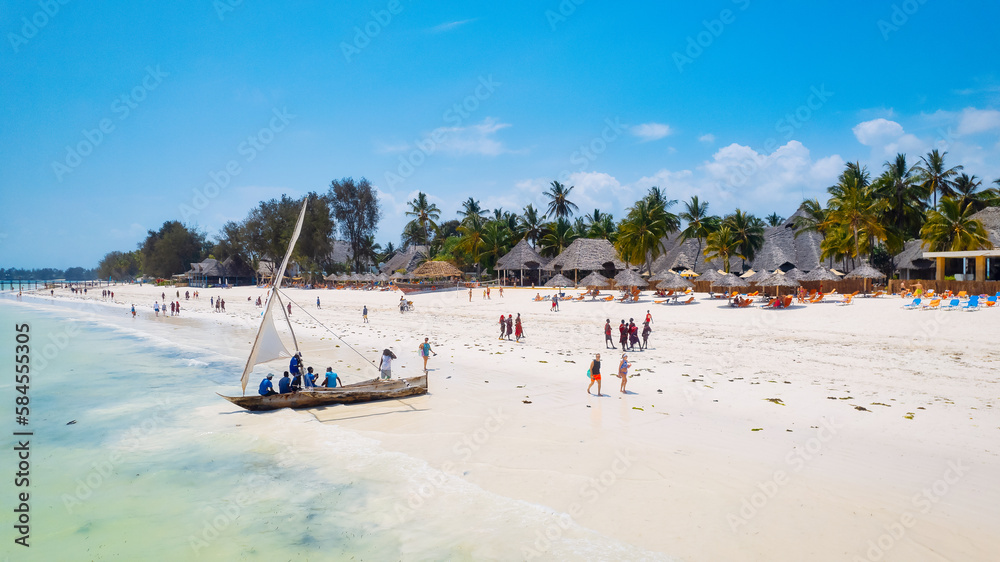 Take in the breathtaking beauty of Zanzibar's tropical coastline from above, as fishing boats dot the sandy beach at sunrise. The view from the top highlights a clear blue sea, green palm trees, Take in the breathtaking beauty of Zanzibar's tropical coastline from above, as fishing boats dot the sandy beach at sunrise. The view from the top highlights a clear blue sea, green palm trees,