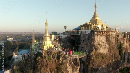 Ascending drone shot showing people exploring hidden Sri Mingala Taung Taw Temple Ares during sunset in Loikaw, Myanmar photo