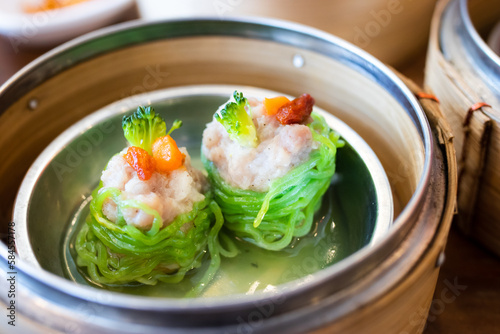 Shrimp dumplings wrapped in jade noodles in a dim sum steamer, a filling and delicious breakfast.