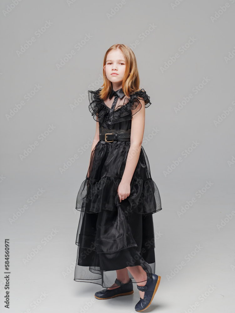 cute blonde teen girl in a black long curvy dress on a gray background. cute blonde teen girl in a black long curvy dress on a gray background.
