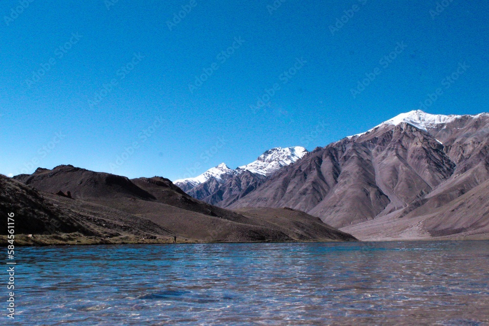 Chandratal Lake is a crescent-shaped high-altitude lake in Spiti, India. Surrounded by mountains and barren landscapes, it has blue-green waters and a serene ambiance, making it a popular destination.