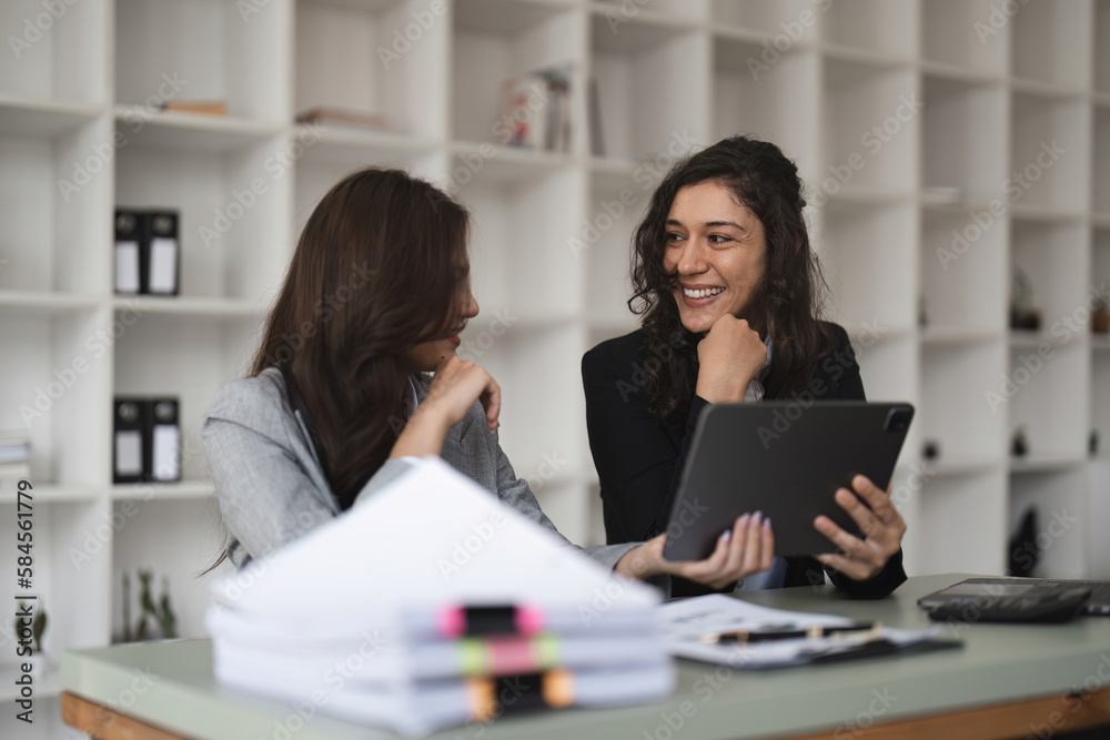 Two smart multiethnic business people working together with laptop while working on project in office Two smart multiethnic business people working together with laptop while working on project in office