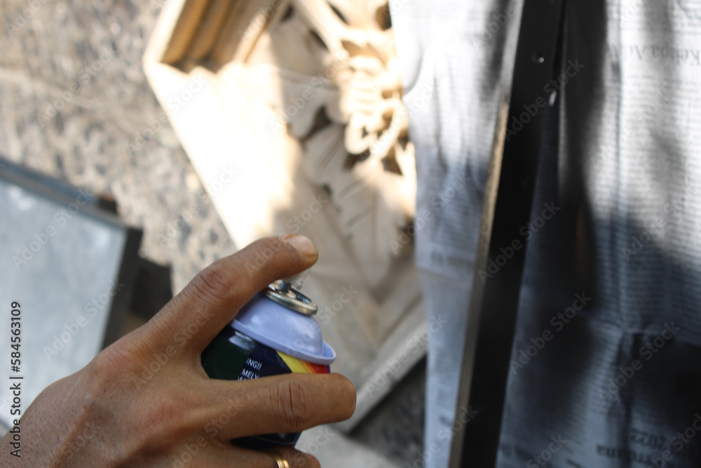 A worker painting steel angle or angle iron in black with spray paint or aerosol paint to create shelves A worker painting steel angle or angle iron in black with spray paint or aerosol paint to create shelves