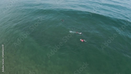 Ocean wave approaches bodyboarders preparing to catch an epic ride photo