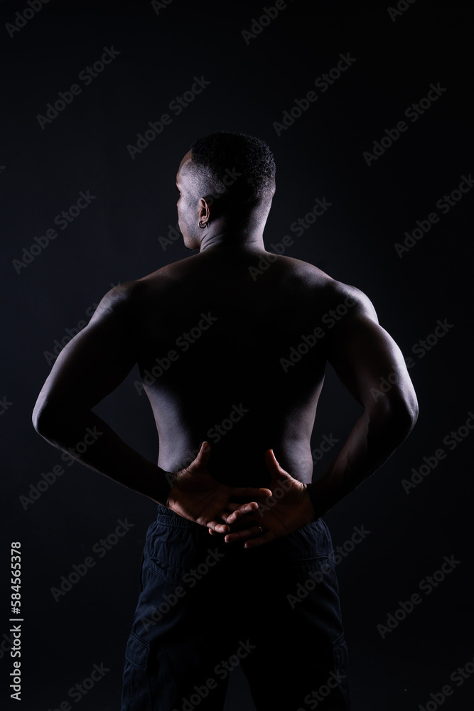 Naklejka premium One young african muscular build man standing topless silhouette isolated on black background