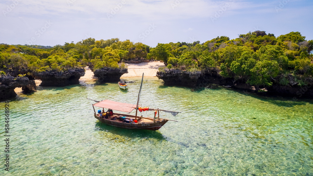 From above, the stunning landscape of Zanzibar's tropical coast comes into focus, with fishing boats lined up on the sandy beach at sunrise. The view from the top reveals a clear blue sea, green palm 