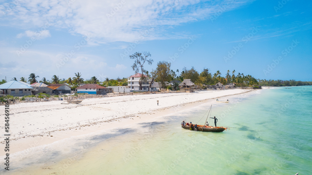 From above, the stunning landscape of Zanzibar's tropical coast comes into focus, with fishing boats lined up on the sandy beach at sunrise. The view from the top reveals a clear blue sea, green palm 