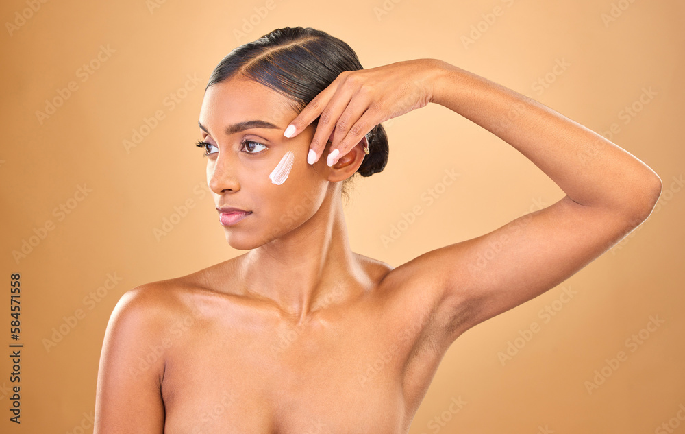 Obraz premium Face, skincare beauty and woman with cream in studio isolated on a brown background. Dermatology idea, cosmetics and thinking Indian female model with lotion, creme or moisturizer for skin health.