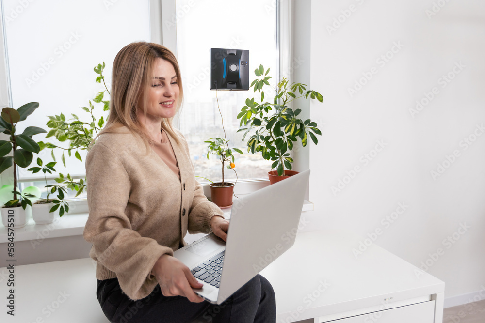 Vacuum cleaner robot cleaning window in high building outdoor. young woman controls the remote. Vacuum cleaner robot cleaning window in high building outdoor. young woman controls the remote.