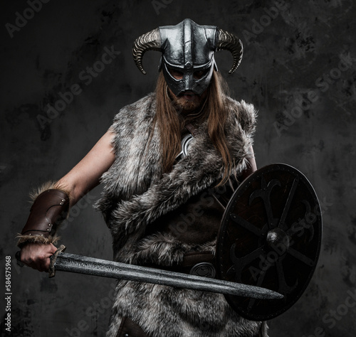 Portrait of barbaric viking dressed in fur posing in fighting stance.