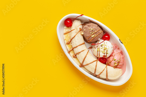 Delicious sweet banana split ice cream dessert with caramel syrup or topping and cherry. Top view. Copy space photo