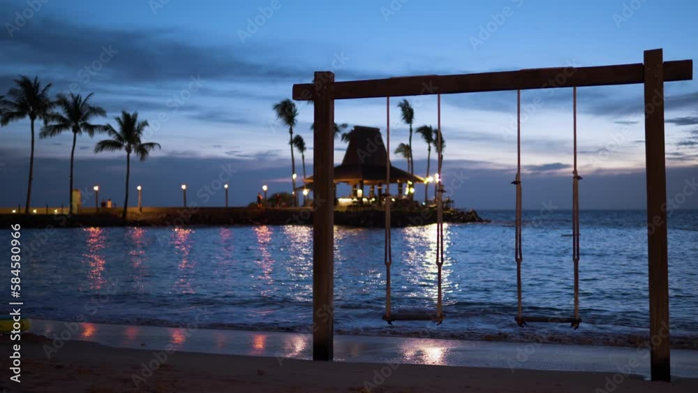 Wooden Rope Swing on Tropical Beach at Shangri-la Resort on Colorful Sundown, Sunset Bar Pavillion in Background Lit With Torches and Sunlight
