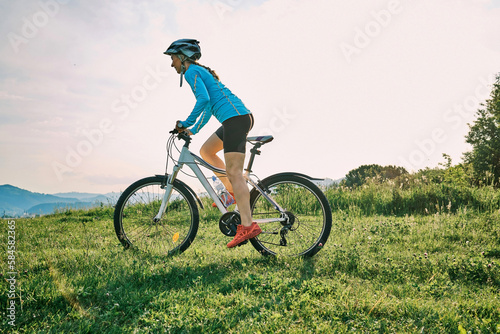 Cyclist Woman riding bike go in sports outdoors on sunny day a mountain in the forest. Silhouette female at sunset. Fresh air. Health care, authenticity, sense of balance and calmness. © Andrii IURLOV