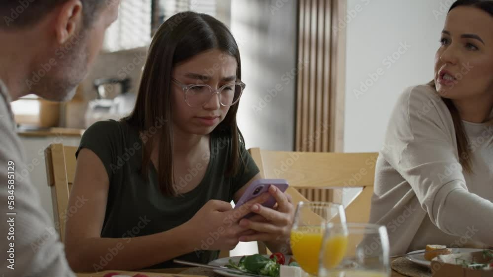 Teenage girl using mobile phone during breakfast at the table. Shot with RED helium camera in 8K. Teenage girl using mobile phone during breakfast at the table. Shot with RED helium camera in 8K.
