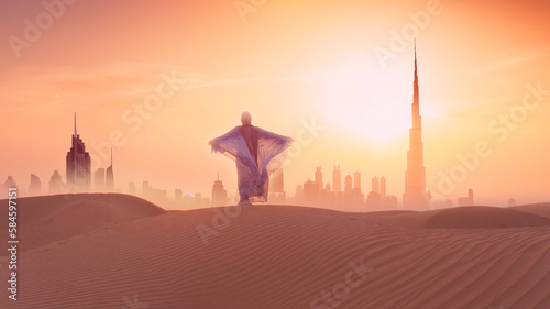 Woman in traditional arab dress stands on the mountains and rises her hand. Dubai city silhouette on the background