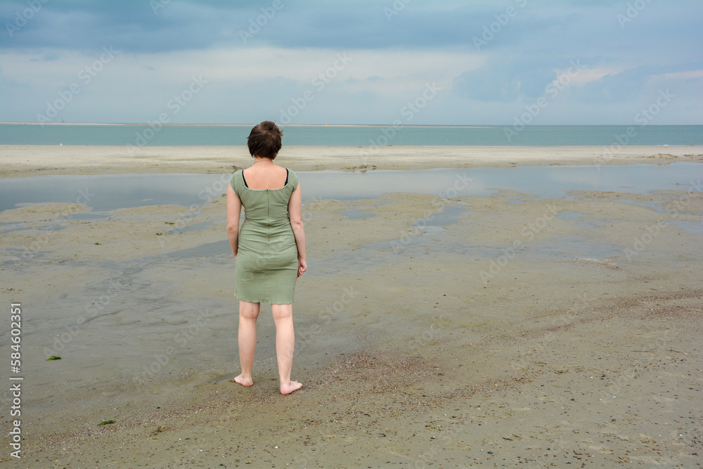 Young woman in dress is standing in front of the sea