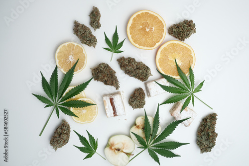 Cannabis buds with leaves and sliced lemon, apple, orange, milky cake. Marijuana terpene concept on white background