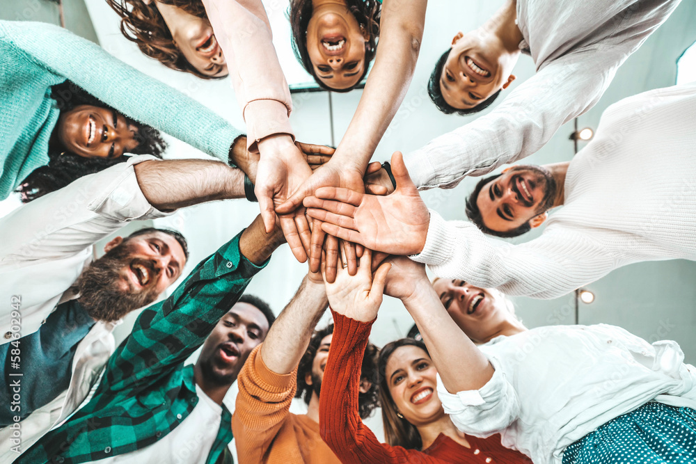 Fototapeta premium Multicultural group of people stacking hands together - University students putting their hands on top of each other - Human relationship, social, community, startup, teambuilding and college concept