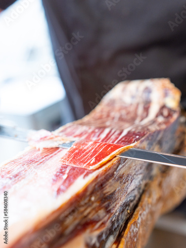 photo detail of a knife cutting serrano ham