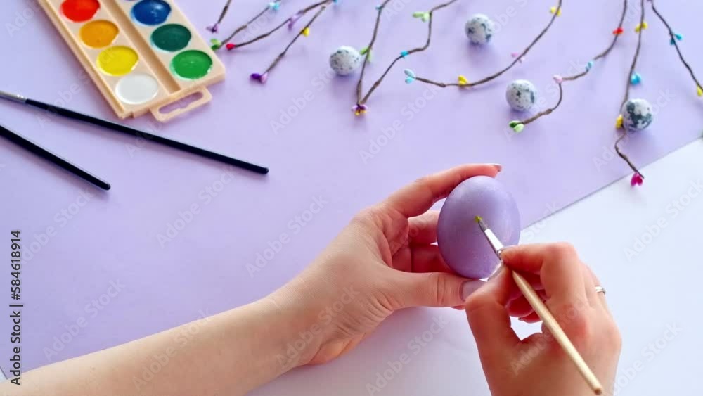 Close-up of woman's hand coloring easter eggs, preparing for the celebration of Easter. Handmade holiday symbols.