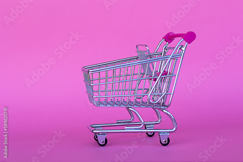 empty shopping cart, pink background, concept of holiday shopping, gift buying, holiday shopping, crisis shopping, discounts and sales