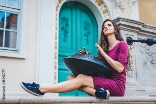 Woman playing hang or hangpan musical instrument on the street. photo