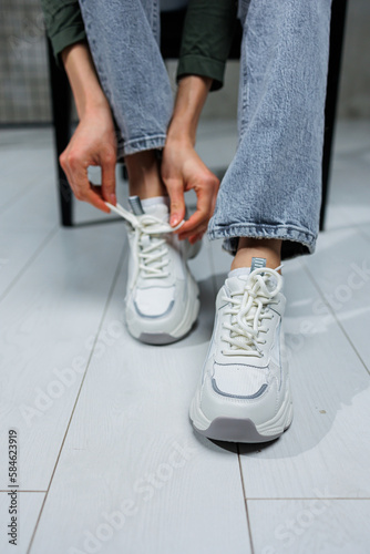 Close-up of female legs in jeans and shoes in fashionable sneakers close-up. Women's everyday fashionable shoes.