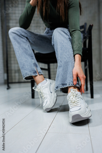 Close-up of female legs in jeans and shoes in fashionable sneakers close-up. Women's everyday fashionable shoes.
