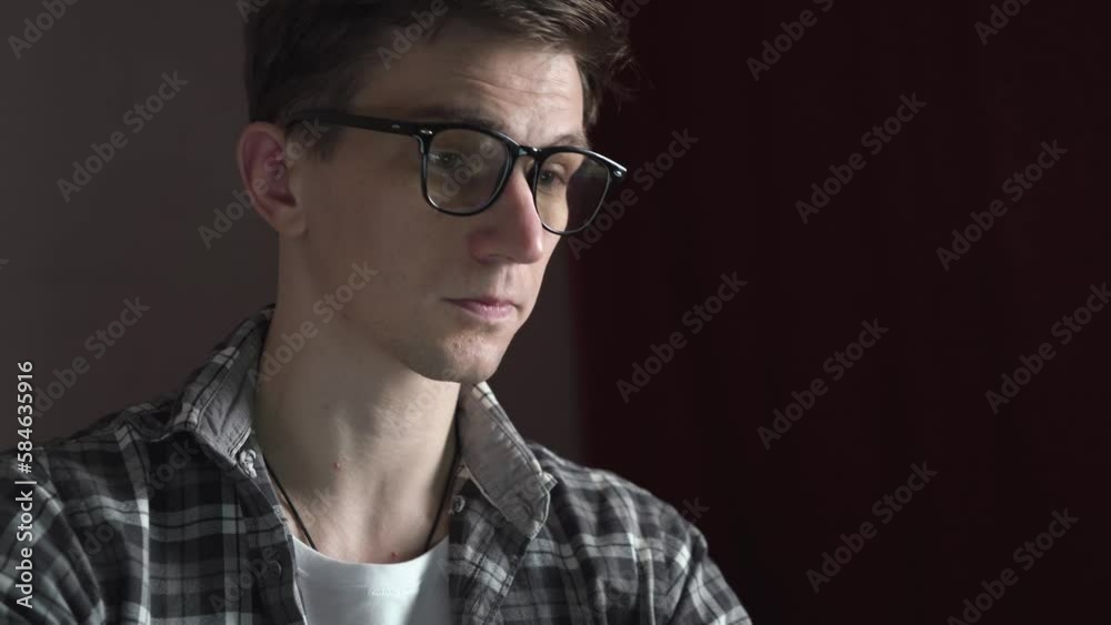 A young man in glasses starts working on a laptop. sliding camera. A young man in glasses starts working on a laptop. sliding camera.