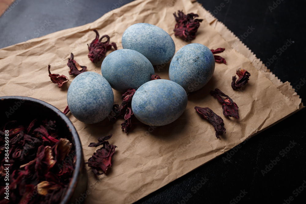 Beautiful DIY painted Easter eggs, dry Hibiscus tea in black bowl. Easter black wooden background. Close up shot