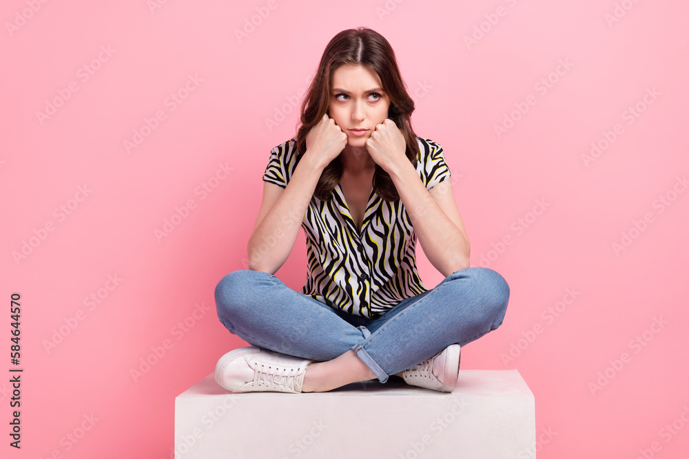 Full length photo of capricious young person sit podium hands touch cheeks look empty space isolated on pink color background - obrazy, fototapety, plakaty 