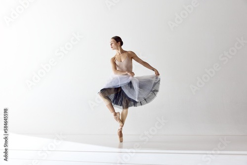 One adotable ballerina holding tutu and dancing over white background