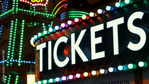 Tickets sign lights up the night at the amusement park entrance. A symbol of entertainment and recreation, bright and colorful sign of entertainment, it invites visitors to join the fun.