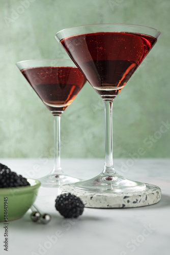 Two blackberry cocktails against a green background