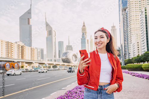 Photography Happy asian student girl using smartphone on the busy Sheikh Zayed road in the center of Dubai city
