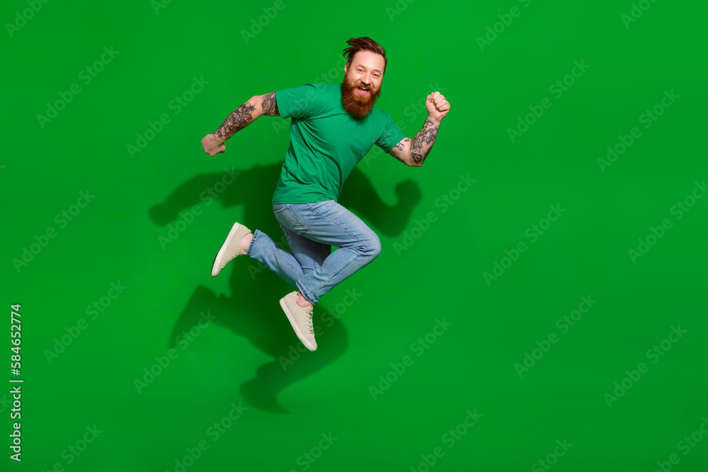 Full length photo of brutal excited guy with ginger beard dressed stylish t-shirt hurry running to sale isolated on green color background