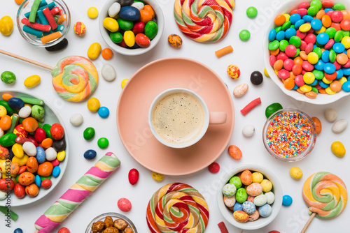 Coffee cup with chocolates and colored candy. Top view on table background with copy space