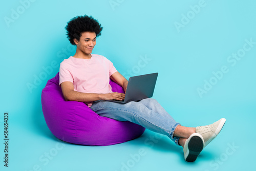 Full body size image of young student man free time chatting with pen friends remote messenger dormitory pouf isolated on aquamarine color background