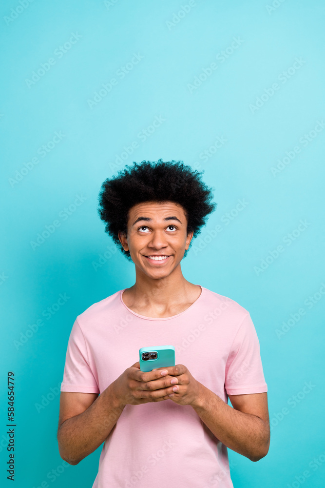 Vertical photo of young funny positive guy chevelure hairstyle hold smartphone look up empty space order food isolated on cyan color background Vertical photo of young funny positive guy chevelure hairstyle hold smartphone look up empty space order food isolated on cyan color background