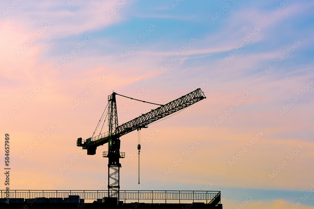 Construction site. Silhouette of a construction crane against the bright evening sky.
