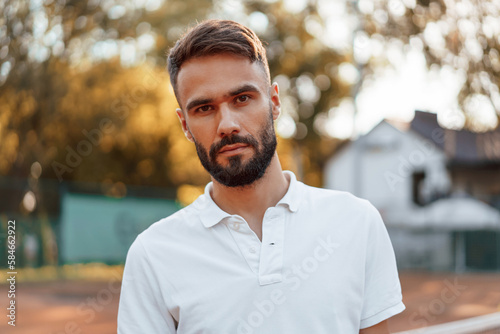 Beautiful portrait. Young man is on the tennis court at sunny daytime