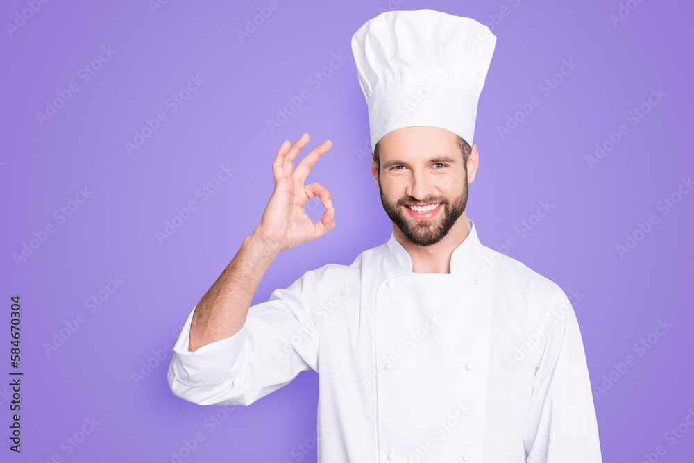 Portrait of cheerful joyful chef cook in beret and white outfit with stubble looking at camera showing ok sign, approve, advice menu isolated on grey background Portrait of cheerful joyful chef cook in beret and white outfit with stubble looking at camera showing ok sign, approve, advice menu isolated on grey background